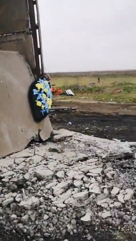 Цвинтарний вінок з кольорами українського прапора на ангарі з уламками техніки армії рф на Херсонщині