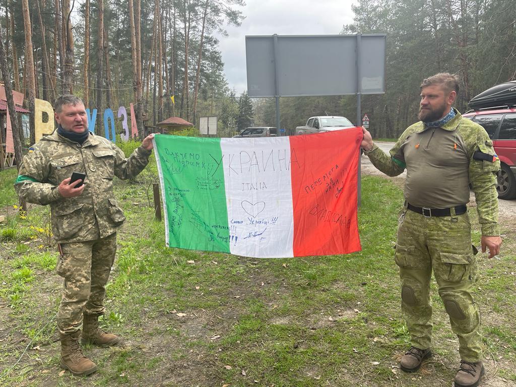Прапор з подяками українців бійців передали італійським журналістам на знак подяки за допомогу