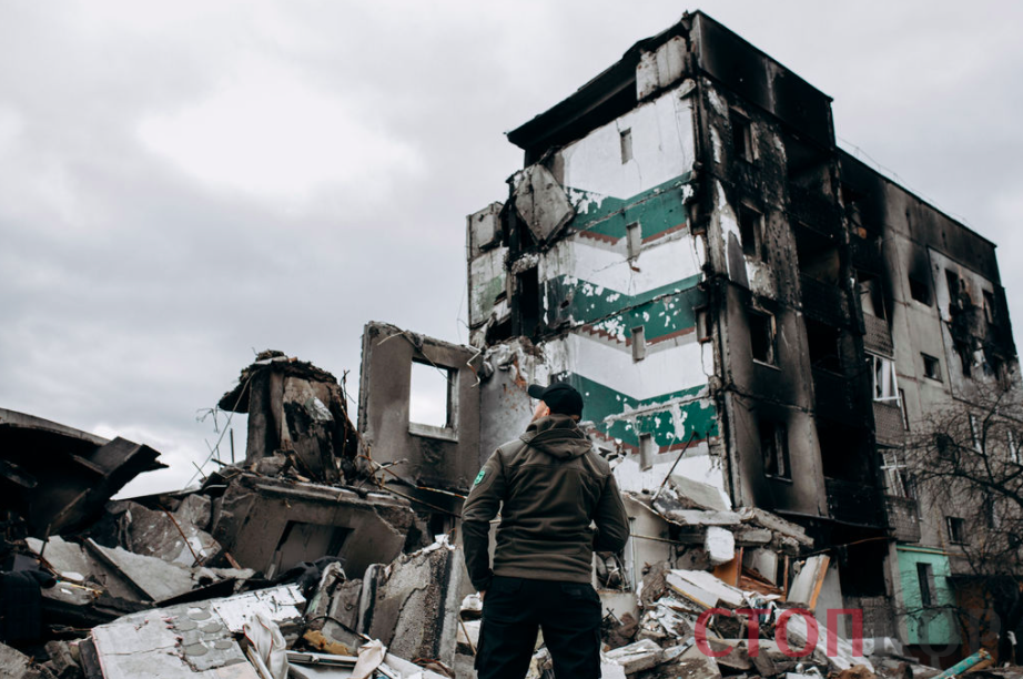 человек на фоне уничтоженного дома