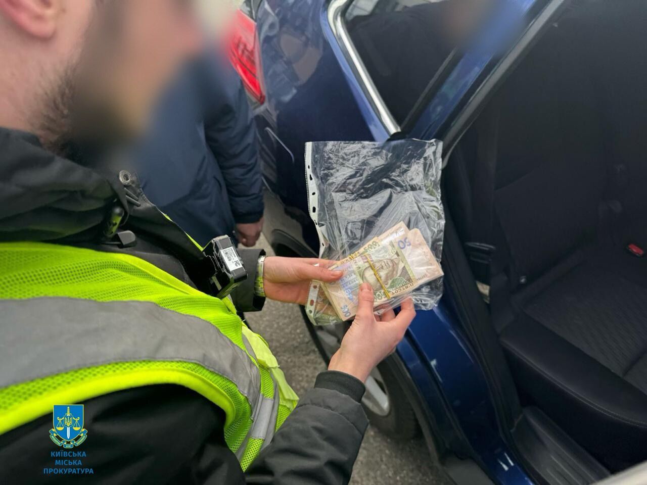 Працівник поліції тримає в руках гроші