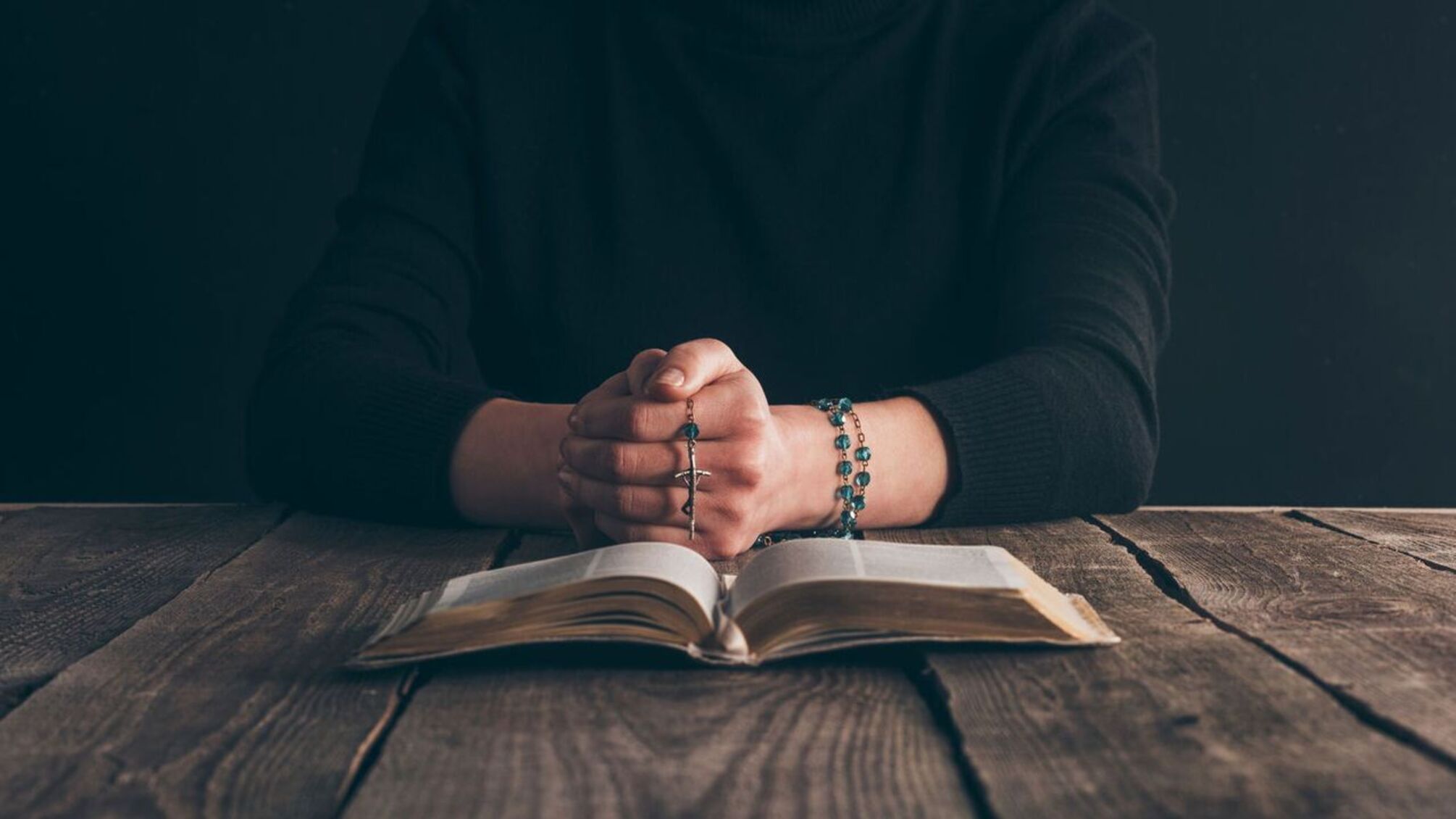 Руки з вервицею біля Святого Письма