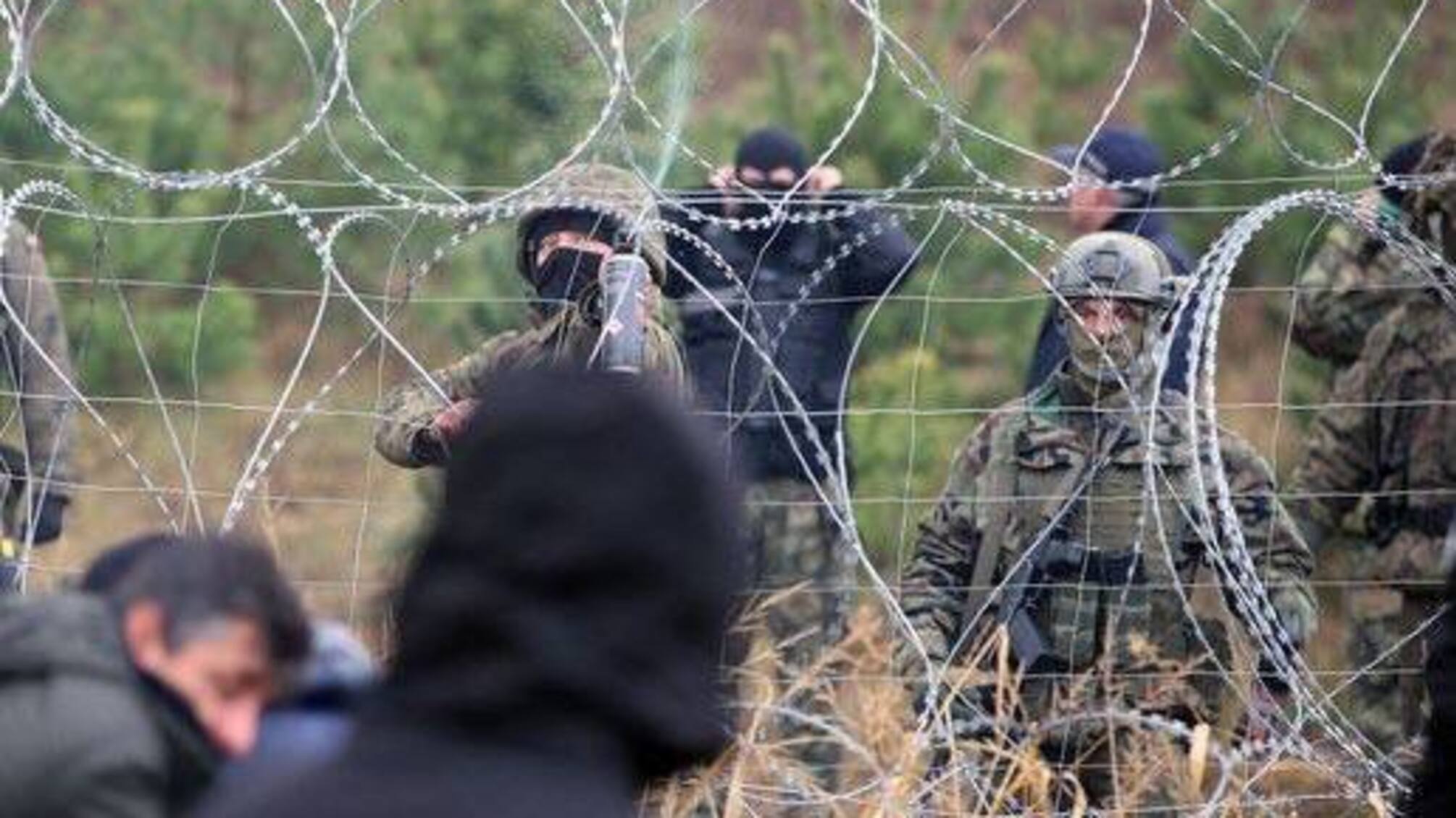 Чоловіки у військовій формі біля колючого дрота