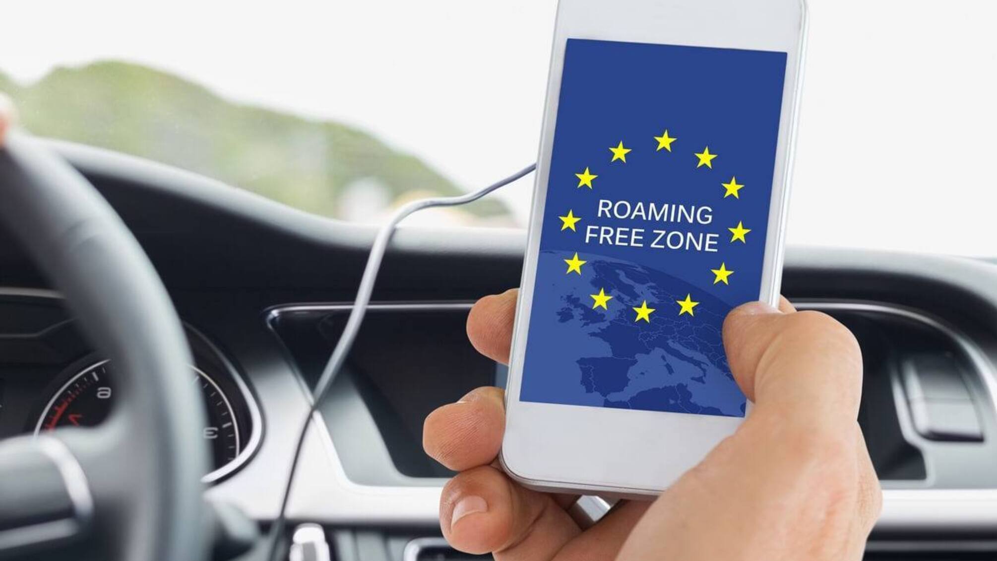 білий смартфон в руках на фоні керма